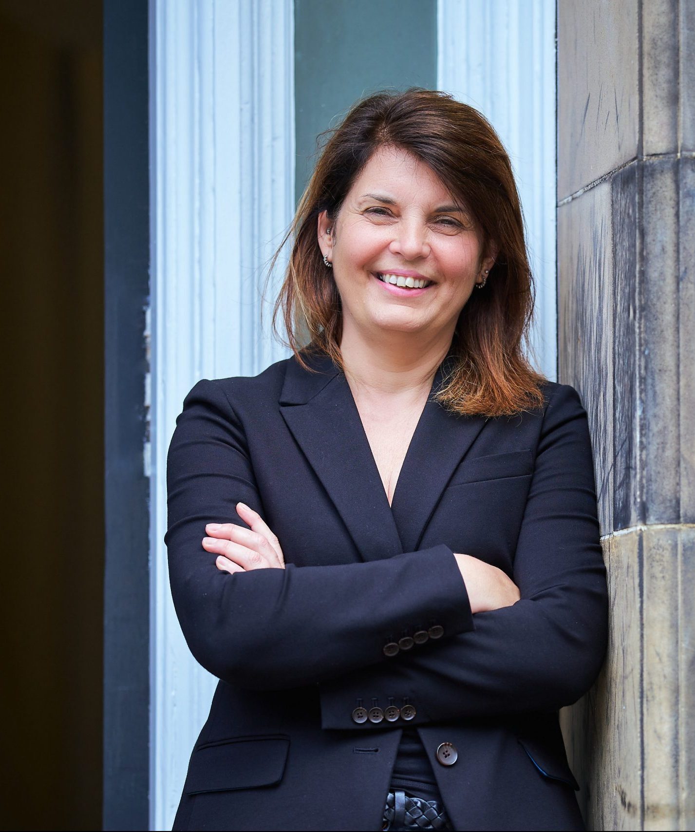 Woman wearing dark blazer and dark jeans.